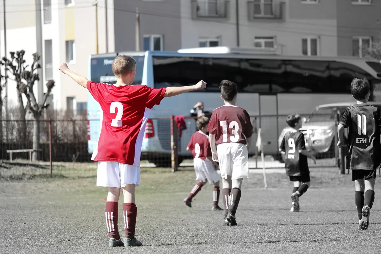 Balón de fútbol sobre el césped de un campo de barrio